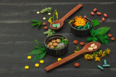 Bitki bazlı takviyeler, taze otlar ve çiçeklerle birlikte doğal vitaminler. Organik maddeler, bütünsel sağlık kavramlarını, alternatif yaşam tarzını öneriyor. Koyu tahta arkaplan, boşluğu kopyala
