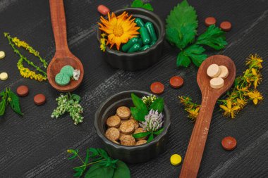 Bitki bazlı takviyeler, taze otlar ve çiçeklerle birlikte doğal vitaminler. Organik maddeler, bütünsel sağlık kavramlarını, alternatif yaşam tarzını öneriyor. Koyu ahşap arka plan, kapat