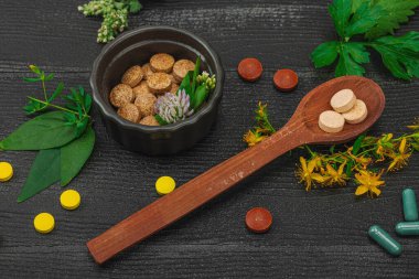 Bitki bazlı takviyeler, taze otlar ve çiçeklerle birlikte doğal vitaminler. Organik maddeler, bütünsel sağlık kavramlarını, alternatif yaşam tarzını öneriyor. Koyu ahşap arka plan, kapat