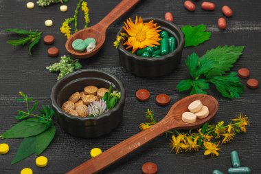 Bitki bazlı takviyeler, taze otlar ve çiçeklerle birlikte doğal vitaminler. Organik maddeler, bütünsel sağlık kavramlarını, alternatif yaşam tarzını öneriyor. Koyu ahşap arka plan, kapat