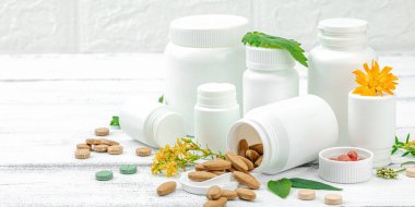 Bitki bazlı takviyeler, taze otlar ve çiçeklerle birlikte doğal vitaminler. Organik maddeler, bütünsel sağlık kavramlarını, alternatif yaşam tarzını öneriyor. Beyaz arkaplan, pankart biçimi