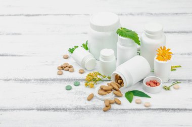 Bitki bazlı takviyeler, taze otlar ve çiçeklerle birlikte doğal vitaminler. Organik maddeler, bütünsel sağlık kavramlarını, alternatif yaşam tarzını öneriyor. Beyaz arkaplan, alanı kopyala