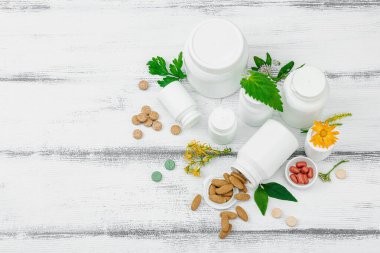 Bitki bazlı takviyeler, taze otlar ve çiçeklerle birlikte doğal vitaminler. Organik maddeler, bütünsel sağlık kavramlarını, alternatif yaşam tarzını öneriyor. Beyaz arkaplan, üst görünüm