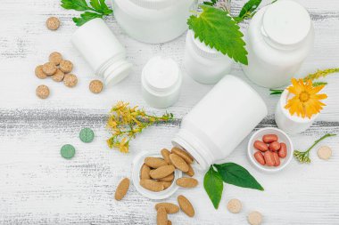 Bitki bazlı takviyeler, taze otlar ve çiçeklerle birlikte doğal vitaminler. Organik maddeler, bütünsel sağlık kavramlarını, alternatif yaşam tarzını öneriyor. Beyaz arkaplan, üst görünüm