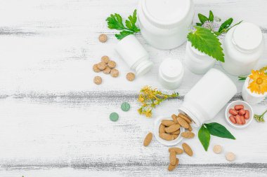 Bitki bazlı takviyeler, taze otlar ve çiçeklerle birlikte doğal vitaminler. Organik maddeler, bütünsel sağlık kavramlarını, alternatif yaşam tarzını öneriyor. Beyaz arkaplan, üst görünüm