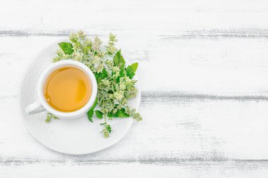 Beyaz ahşap arka planda limonlu çay. Yenilebilir taze otlar, modaya uygun içecekler. Organik sağlık hizmetleri, eko yaşam tarzı, vejetaryen içeceği, üst görünüm