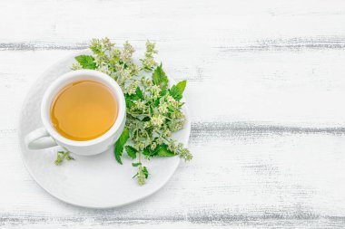 Beyaz ahşap arka planda limonlu çay. Yenilebilir taze otlar, modaya uygun içecekler. Organik sağlık hizmetleri, eko yaşam tarzı, vejetaryen içeceği, üst görünüm