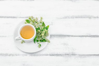Beyaz ahşap arka planda limonlu çay. Yenilebilir taze otlar, modaya uygun içecekler. Organik sağlık hizmetleri, eko yaşam tarzı, vejetaryen içeceği, üst görünüm