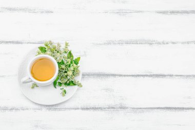 Beyaz ahşap arka planda limonlu çay. Yenilebilir taze otlar, modaya uygun içecekler. Organik sağlık hizmetleri, eko yaşam tarzı, vejetaryen içeceği, üst görünüm