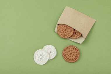 Crochet face scrubby cotton pads. Handmade reusable accessories for eco beauty routine. Zero waste useful concept, trendy green background, flat lay, top view clipart