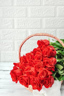 Beyaz arka planda sepette bir buket kırmızı gül. Çiçek açan, Anneler Günü ya da Sevgililer Günü için neşeli bir konsept. Tebrik kartı, Paskalya düzlüğü, en iyi dileklerimle, kopyalama alanı
