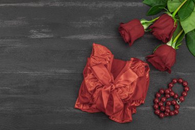 Kırmızı güller, kolye ve siyah arka planda dantel peignoir. Çiçek açan, romantik sevgililer günü. Tebrik kartı, festival konsepti, düz konum, üst görünüm