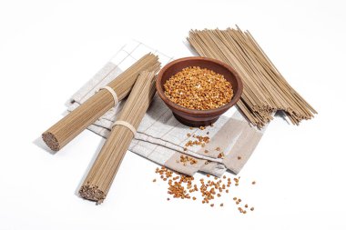 Japon karabuğday sobalı erişte. Geleneksel yemekleri hazırlamak için klasik malzeme. Seramik kase, keten peçete. Sert ışık, koyu gölge, beyaz arkaplan, boşluğu kopyala