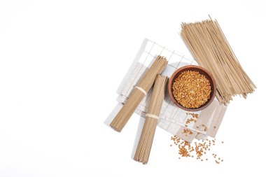 Japon karabuğday sobalı erişte. Geleneksel yemekleri hazırlamak için klasik malzeme. Seramik kase, keten peçete. Sert ışık, koyu gölge, beyaz arkaplan, üst görünüm