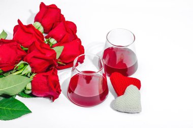 Romantik randevu kavramı. İki kadeh şarap, el yapımı kalpler, bir buket kırmızı gül. Moda sabit ışık, koyu gölge, beyaz arkaplan, düz yatış, kopyalama alanı