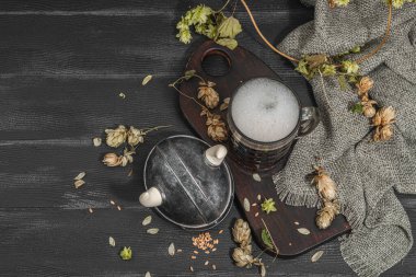 Yaratıcı Oktoberfest kompozisyonu. Koyu bira, Viking kaskı, zıpla ve buğday. Alman festivali yemek konsepti. Modaya uygun sert ışık, koyu gölge, klasik siyah arkaplan, üst görünüm