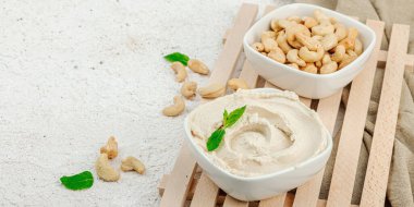 Ev yapımı vejetaryen kaju peyniri. Tabakta çiğ sağlıklı sos, laktozsuz yemek. Biyolojik organik ürün, bitki temelli diyet, alternatif yaşam tarzı. Hafif taş arkaplan, pankart biçimi