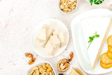 Çeşitli ev yapımı vejetaryen fındık peyniri seti. Tabakta çiğ sağlıklı sos, laktozsuz yemek. Biyolojik organik ürün, bitki temelli diyet, alternatif yaşam tarzı. Işık taşı arkaplan, üst görünüm