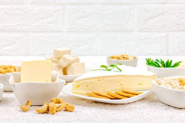 Çeşitli ev yapımı vejetaryen fındık peyniri seti. Tabakta çiğ sağlıklı sos, laktozsuz yemek. Biyolojik organik ürün, bitki temelli diyet, alternatif yaşam tarzı. Işık taşı arkaplanı, boşluğu kopyala