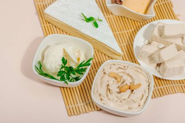 Çeşitli ev yapımı vejetaryen fındık peyniri seti. Tabakta çiğ sağlıklı sos, laktozsuz yemek. Biyolojik organik ürün, bitki temelli diyet, alternatif yaşam tarzı. Şeftali rengi arka plan, kapat.