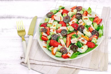 Çilekli taze salata, yapraklar, peynir, olgun üzüm ve füme tavuk. Haşhaş tohumlu leziz bir sos, geleneksel sağlıklı yiyecek yaşam tarzı. Beyaz ahşap arka plan, kapat