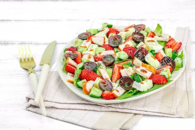 Çilekli taze salata, yapraklar, peynir, olgun üzüm ve füme tavuk. Haşhaş tohumlu leziz bir sos, geleneksel sağlıklı yiyecek yaşam tarzı. Beyaz tahta arkaplan, boşluğu kopyala