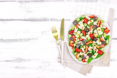 Çilekli taze salata, yapraklar, peynir, olgun üzüm ve füme tavuk. Haşhaş tohumlu leziz bir sos, geleneksel sağlıklı yiyecek yaşam tarzı. Beyaz ahşap arkaplan, üst görünüm