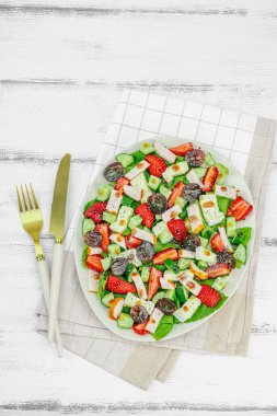 Fresh salad with strawberry, leaves mix, brie cheese, ripe grape and smoked chicken. Delicious dressing with poppy seeds, traditional healthy food lifestyle. White wooden background, top view clipart