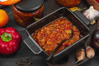 Sebze havyarı, geleneksel vejetaryen yahnisi, sote. Olgun sebzeler, mis kokulu baharatlar, yiyecek konseptini muhafaza etmek. Rahat ve nostaljik ruh hali, siyah ahşap arka plan, yakın çekim.