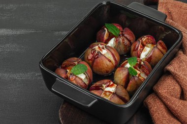 Peynirli peynirli, otlu ve ballı fırında incir. Sağlıklı yiyecekler, mevsimlik meyveler, lezzetli atıştırmalıklar. Siyah tahta arkaplan, boşluğu kopyala