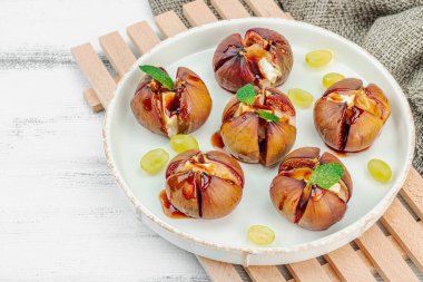 Peynirli peynirli, otlu ve ballı fırında incir. Sağlıklı yiyecekler, mevsimlik meyveler, lezzetli atıştırmalıklar. Beyaz tahta arkaplan, boşluğu kopyala