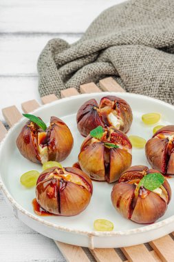 Peynirli peynirli, otlu ve ballı fırında incir. Sağlıklı yiyecekler, mevsimlik meyveler, lezzetli atıştırmalıklar. Beyaz tahta arkaplan, boşluğu kopyala