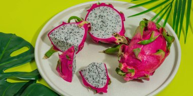 Parlak sarı arka planda taze pitahaya. Ejderha meyvesi hasadı, tropikal ürün. Meyve suyu, salata ya da içecek için sağlıklı malzeme. Sert ışık, koyu gölge, düz uzanma, afiş biçimi