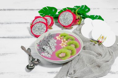 Meyve, kivi, muz ve haşhaş tohumlu Pitaya smoothie kasesi. Moda yemek, sağlıklı kahvaltı fikri. Sert ışık, karanlık gölge, beyaz ahşap zemin, kopyalama alanı