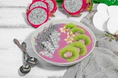 Meyve, kivi, muz ve haşhaş tohumlu Pitaya smoothie kasesi. Moda yemek, sağlıklı kahvaltı fikri. Sert ışık, karanlık gölge, beyaz ahşap zemin, kopyalama alanı