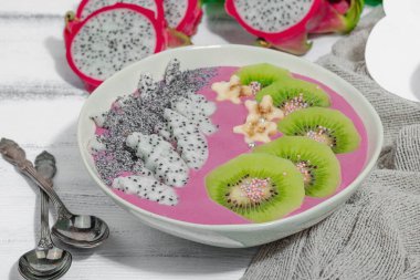 Meyve, kivi, muz ve haşhaş tohumlu Pitaya smoothie kasesi. Moda yemek, sağlıklı kahvaltı fikri. Sert ışık, karanlık gölge, beyaz ahşap zemin, kapat