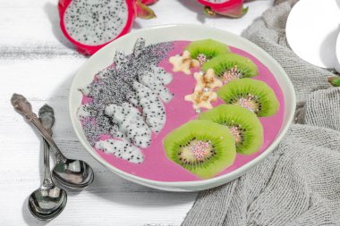 Meyve, kivi, muz ve haşhaş tohumlu Pitaya smoothie kasesi. Moda yemek, sağlıklı kahvaltı fikri. Sert ışık, karanlık gölge, beyaz ahşap zemin, kapat