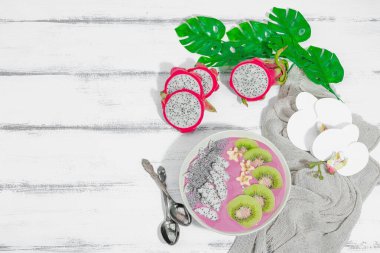 Meyve, kivi, muz ve haşhaş tohumlu Pitaya smoothie kasesi. Moda yemek, sağlıklı kahvaltı fikri. Sert ışık, karanlık gölge, beyaz ahşap zemin, üst manzara