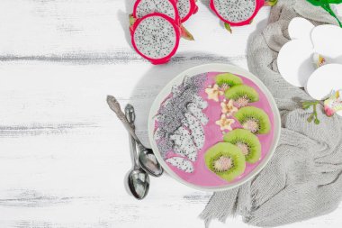 Meyve, kivi, muz ve haşhaş tohumlu Pitaya smoothie kasesi. Moda yemek, sağlıklı kahvaltı fikri. Sert ışık, karanlık gölge, beyaz ahşap zemin, üst manzara