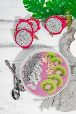 Meyve, kivi, muz ve haşhaş tohumlu Pitaya smoothie kasesi. Moda yemek, sağlıklı kahvaltı fikri. Sert ışık, karanlık gölge, beyaz ahşap zemin, üst manzara