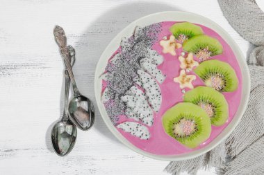 Meyve, kivi, muz ve haşhaş tohumlu Pitaya smoothie kasesi. Moda yemek, sağlıklı kahvaltı fikri. Sert ışık, karanlık gölge, beyaz ahşap zemin, üst manzara