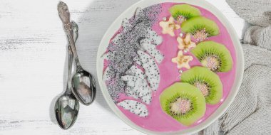 Meyve, kivi, muz ve haşhaş tohumlu Pitaya smoothie kasesi. Moda yemek, sağlıklı kahvaltı fikri. Sert ışık, karanlık gölge, beyaz ahşap zemin, üst manzara