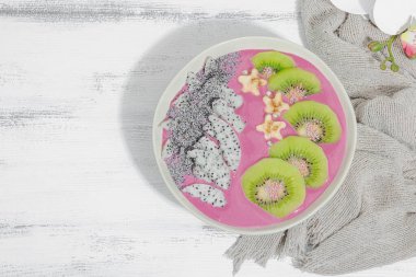 Meyve, kivi, muz ve haşhaş tohumlu Pitaya smoothie kasesi. Moda yemek, sağlıklı kahvaltı fikri. Sert ışık, karanlık gölge, beyaz ahşap zemin, üst manzara