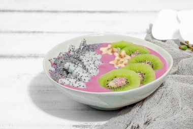 Meyve, kivi, muz ve haşhaş tohumlu Pitaya smoothie kasesi. Moda yemek, sağlıklı kahvaltı fikri. Sert ışık, karanlık gölge, beyaz ahşap zemin, kopyalama alanı