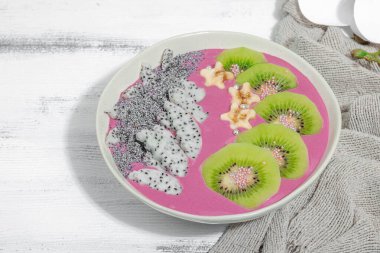 Meyve, kivi, muz ve haşhaş tohumlu Pitaya smoothie kasesi. Moda yemek, sağlıklı kahvaltı fikri. Sert ışık, karanlık gölge, beyaz ahşap zemin, kopyalama alanı