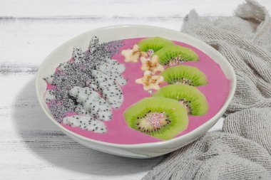 Meyve, kivi, muz ve haşhaş tohumlu Pitaya smoothie kasesi. Moda yemek, sağlıklı kahvaltı fikri. Sert ışık, karanlık gölge, beyaz ahşap zemin, kapat