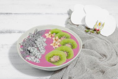 Meyve, kivi, muz ve haşhaş tohumlu Pitaya smoothie kasesi. Moda yemek, sağlıklı kahvaltı fikri. Sert ışık, karanlık gölge, beyaz ahşap zemin, kopyalama alanı