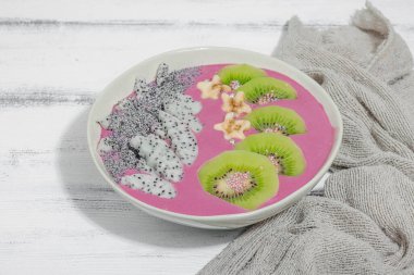 Meyve, kivi, muz ve haşhaş tohumlu Pitaya smoothie kasesi. Moda yemek, sağlıklı kahvaltı fikri. Sert ışık, karanlık gölge, beyaz ahşap zemin, kopyalama alanı