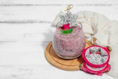 Pitaya smoothie, sağlıklı detoks içeceği. Moda içecek, yararlı kahvaltı fikri. Sert ışık, karanlık gölge, beyaz ahşap zemin, kopyalama alanı
