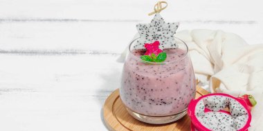 Pitaya smoothie, sağlıklı detoks içeceği. Moda içecek, yararlı kahvaltı fikri. Sert ışık, koyu gölge, beyaz ahşap arkaplan, afiş biçimi